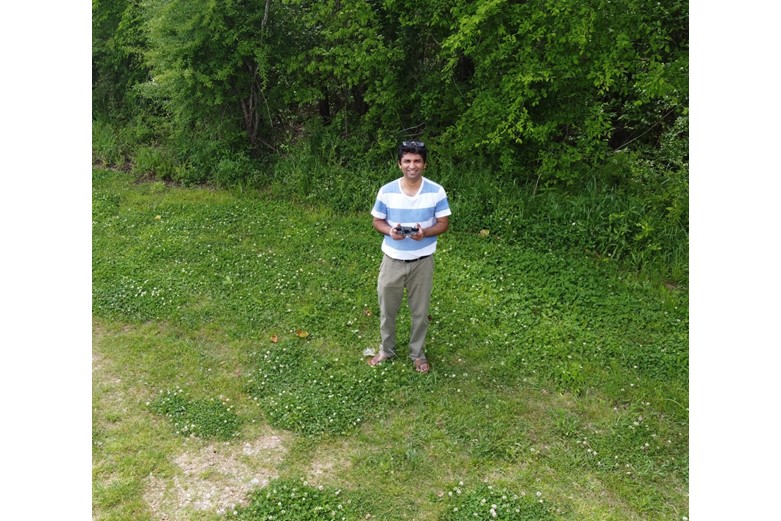 A man stands in a grassy field with a smile on his face