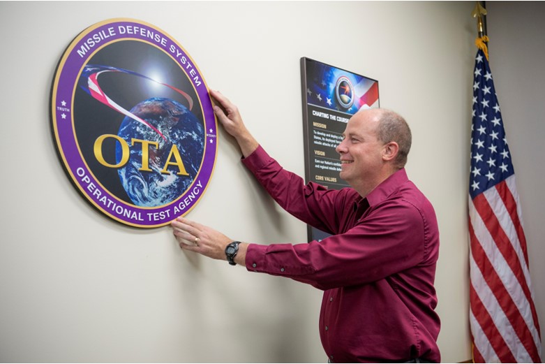 A man places a circular crest on a wall