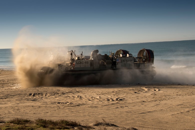 A hovercraft lands on a beach.