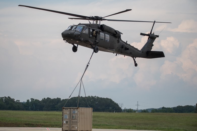 A helicopter is lifting up a storage crate.