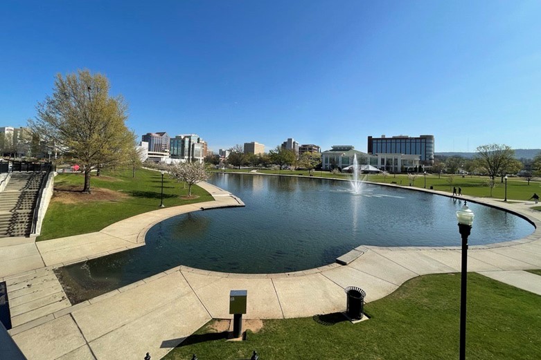 An outdoor scene of a public park with a large pool and fountain