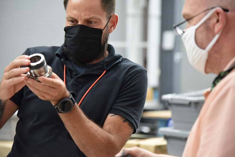 Two ATEC contractors inspect a bolt that is used by an apache helicopter. 